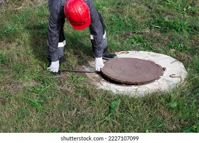 A male plumber opens a water well with a crowbar. Inspection and repair of water wells and septic tanks. - Shutterstock ID 2227107099