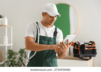 Male plumber using tablet computer in bathroom