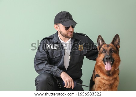 Male police officer with dog on color background
