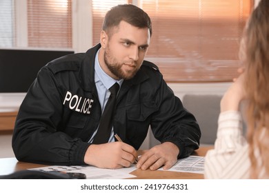 Male police officer working with victim in office