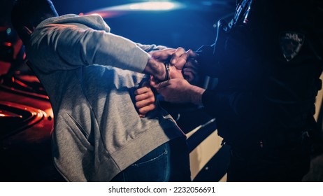 Male Policeman Forcing a Compliant Civilian on the Hood of Police Car. Officer Violently Pushing Man Against the Car and Handcuffing Him. Shocking Case of Police Brutality. Close up on Hands