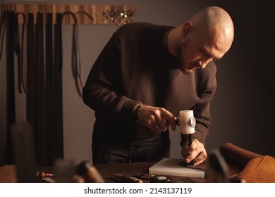 male portrait tanner makes leather wallet, professional craftsman, business. Handiwork. - Powered by Shutterstock