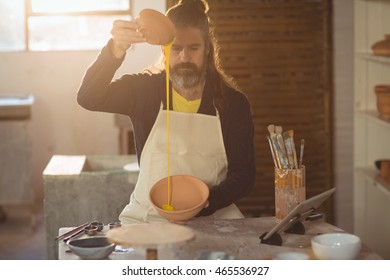 Male potter pouring watercolor in bowl at pottery workshop - Powered by Shutterstock