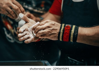 male powerlifter applying gym chalk on his hands before bench press powerlifting competition