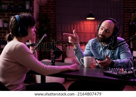 Male presenter interviewing woman on podcast discussion, talking to guest in studio. Young man having conversation with social media blogger, recording show for channel content.