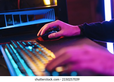 Male pro gamer's hands playing computer video game with professional computer mouse and keyboard. Close up of cyber sportsman hands on gaming equipment. Selective focus on hand. Cyber sport concept
