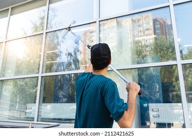 Male professional cleaning service worker in overalls cleans the windows and shop windows of a store with special equipment - Powered by Shutterstock