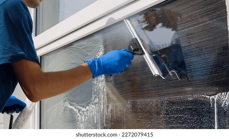 Male professional cleaning service worker in overalls cleans the windows and shop windows of a store with special equipment - Shutterstock ID 2272079415