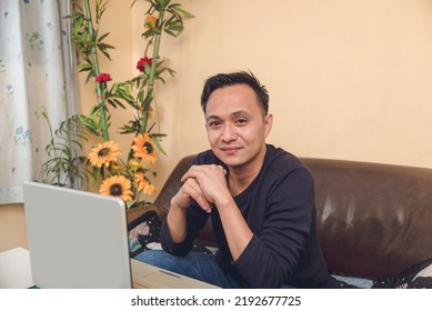 Male Professional Feeling Good, Working On His Laptop Indoors. Man Sitting On A Couch. Portrait Of Happy Outlook.