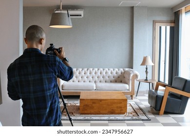 Male professional photographer shooting indoors in the living room, home photography for real estate, selling houses and apartments, including interior design - Shutterstock ID 2347956627