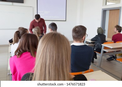 Male professor explain lesson to students and interact with them in the classroom.Helping a students during class.