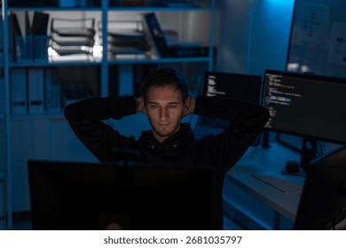 Male programmer developer relaxing after coding software on computer screen monitor in night office