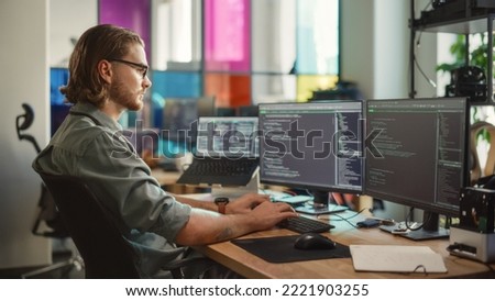 Male Programmer Using Desktop Computer And Laptop To Write Code In Creative Office. Caucasian Man Using Multiple Displays Set Up. Developing Software As A Service Platform For Innovative Start-Up.