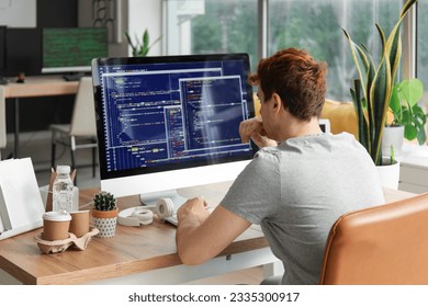 Male programmer working with computer at table in office