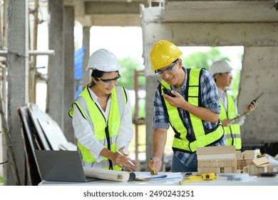 Male project manager and architect woman examining blueprint at building site - Powered by Shutterstock