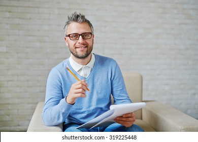 Male Psychiatrist With Pencil And Clipboard Looking At Camera