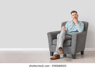 Male Psychologist Sitting In Armchair Near Light Wall