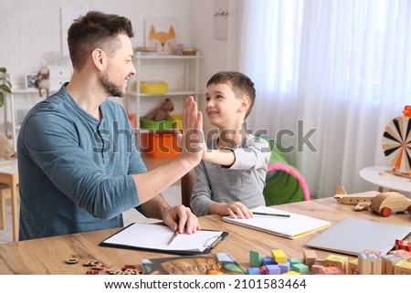 Male psychologist working with little boy in office. Autism concept