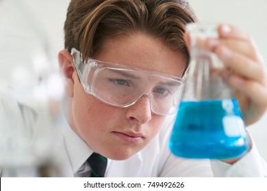 Male Pupil Conducting Chemistry Experiment In Science Class