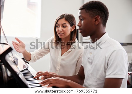 Male Pupil With Teacher Playing Piano In Music Lesson
