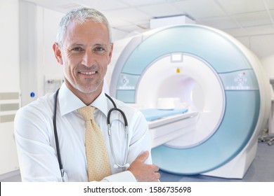 Male Radiographer Standing By MRI Scanner In Hospital