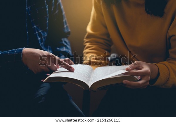 Male\
reading the Holy Bible by pointing to the character and sharing the\
gospel with a friend. Holy Bible study reading together in Sunday\
school.Studying the Word Of God With\
Friends.