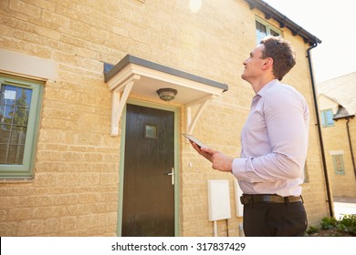 Male real estate agent looking up at a house exterior