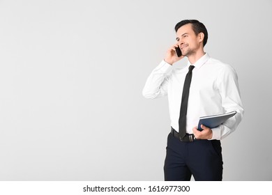 Male Real Estate Agent Talking By Mobile Phone On Light Background