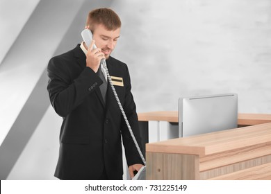 Male receptionist talking on phone in hotel
