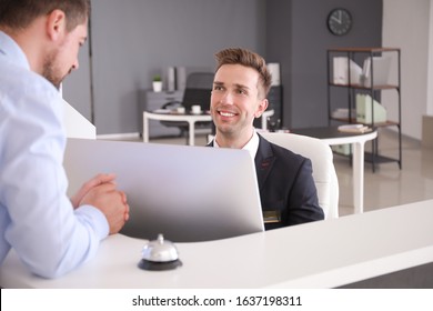 Male receptionist working with visitor in office - Powered by Shutterstock