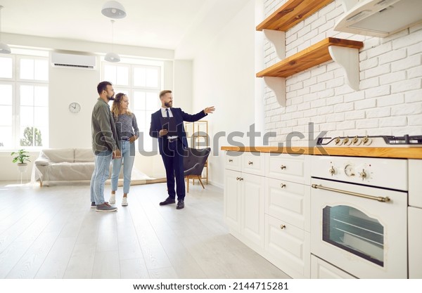 Male\
relator or broker show home to couple buyers or renters buying fist\
dwelling together. Man real estate agent demonstrate apartment to\
tenants. Homeowner, bank loan or mortgage,\
rent.