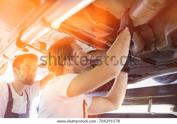 Male repair\
workers examining car in\
workshop