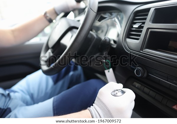 Male repairman in protective gloves holding\
steering wheel in car\
closeup