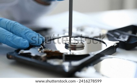 Male repairman wearing blue gloves dismantles specialized professional screwdriver hard drive. Performs fault diagnostics and performs urgent repairs recovery of lost data during deletion HDD closeup