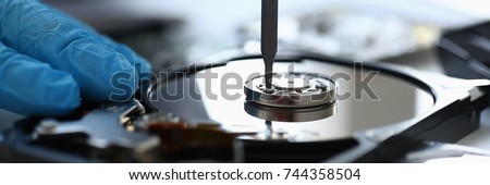 Male repairman wearing blue gloves dismantles specialized professional screwdriver  hard drive. Performs fault diagnostics and performs urgent repairs recovery of lost data during deletion HDD closeup