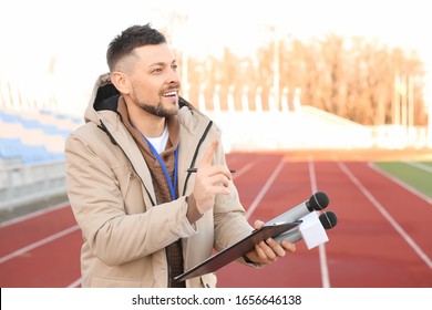 Male reporter with microphones at the stadium - Powered by Shutterstock