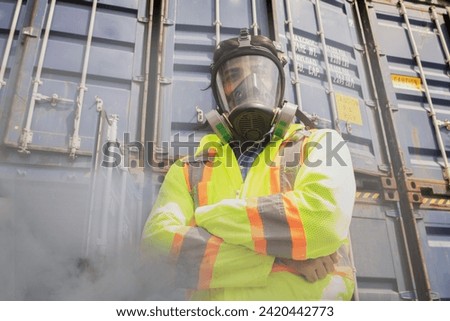 Male rescue worker wearing PPE suit standing with arms crossed wearing mask protect dangerous toxins inspect illegally transported containers prohibit outsiders entering dangerous areas for safety.