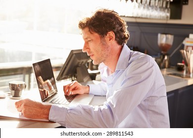 Male Restaurant Manager Working On Laptop