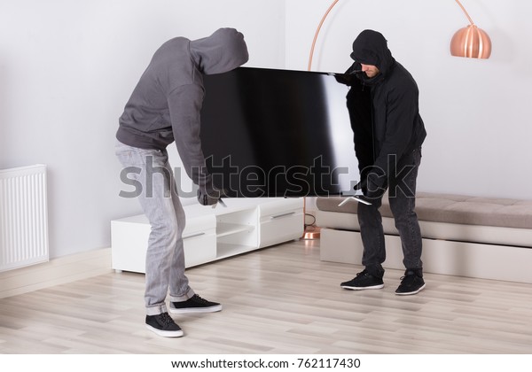 Male\
Robbers In Hood Stealing Television From Living\
Room
