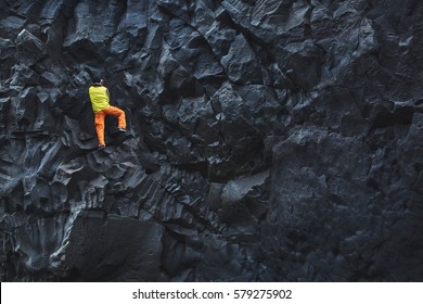 male rock climber. rock climber climbs on a rocky wall on the ocean bank. man makes hard move without rope.