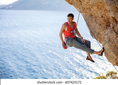 Male rock climber resting while hanging on rope before next attempt on challenging route - Powered by Shutterstock