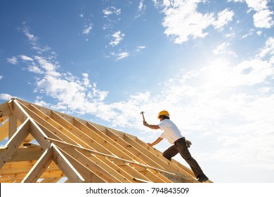 male roofer carpenter working on roof structure on construction site