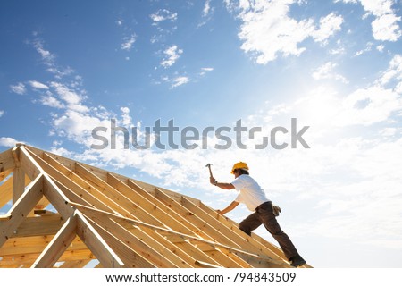 male roofer carpenter working on roof structure on construction site