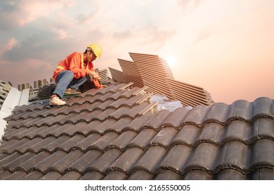 A Male Roofer Uses A Cordless Electric Battery Drill To Fire Screws To Install Concrete Roofing Slabs Or C-packs On Home Structure Construction