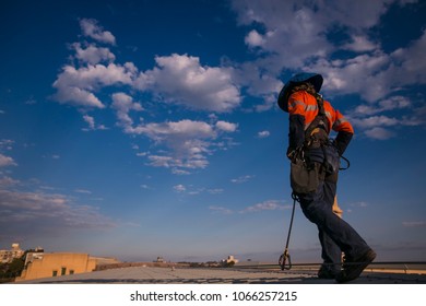 Male Rope Access Industry Contractor,  Site Maintenance Inspection On Construction Building Site By Using His Rope Clipping On Safety Roof Anchor Line, Full Arrest, Strain Fall Protection System 
