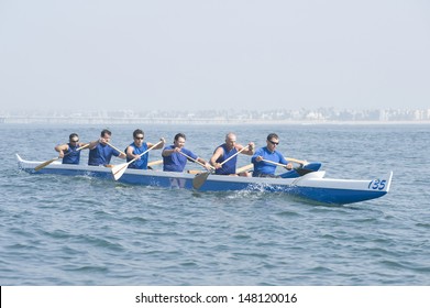 Male rowers paddling outrigger canoe in race