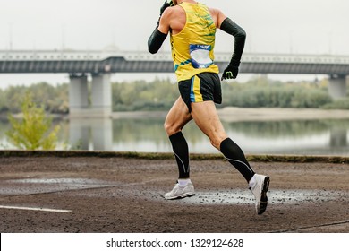 Male Runner In Compression Socks And Protective Arm Sleeves Run River Embankment