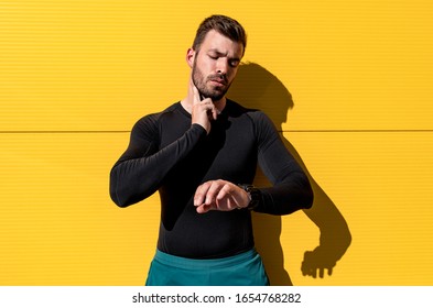 Male runner resting after workout checking pulse isolated on yellow background. - Powered by Shutterstock