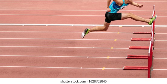 male runner running 110 meters hurdles in athletics competition - Shutterstock ID 1628702845