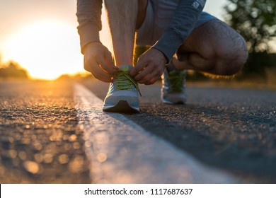 Male Runner Tying Her Shoes Preparing For A Run A Jog Outside